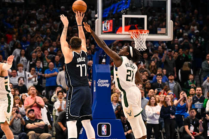 Luka Doncic shoots a 3-pointer over the outstretched arm of Jrue Holiday.